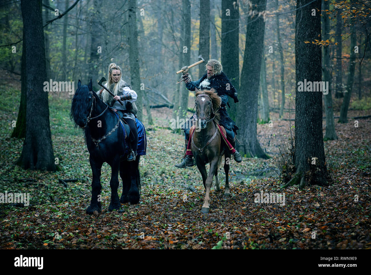 Krieger Frau ein Mann auf Pferde in den Wäldern. Die skandinavischen Wikinger Reiten mit Achsen in den Händen. Traditionelle Kleidung mit Pelzkragen. Reconstructio Stockfoto