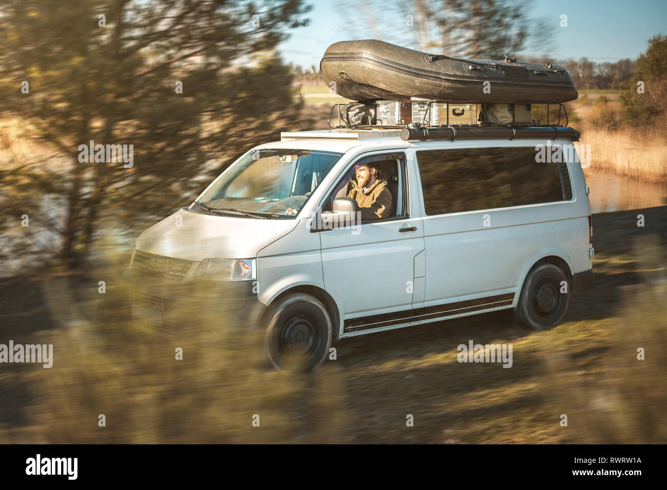 Van mit einem Schlauchboot auf dem Dachgepäckträger fährt durch die Natur  Stockfotografie - Alamy