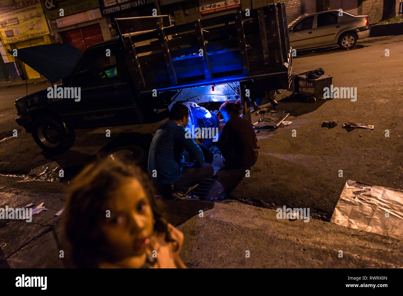 Kolumbianische Kfz-Mechaniker arbeiten auf eine hinterachse von einem Pickup während der Nacht im Barrio Triste, Medellín, Kolumbien. Stockfoto
