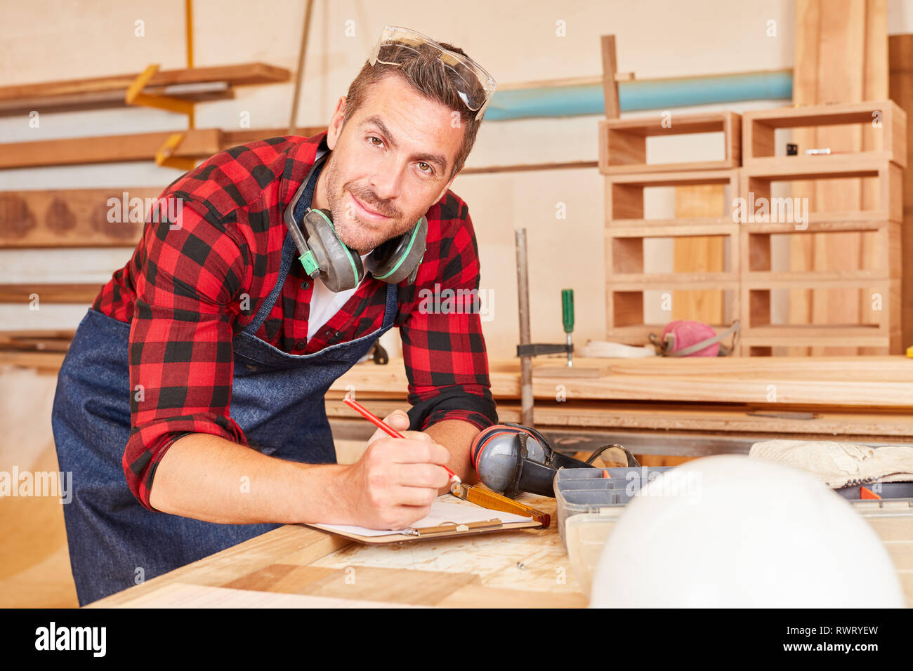 Handwerker mit Klemmbrett und Stift während der Planung in seiner Schreinerei Stockfoto