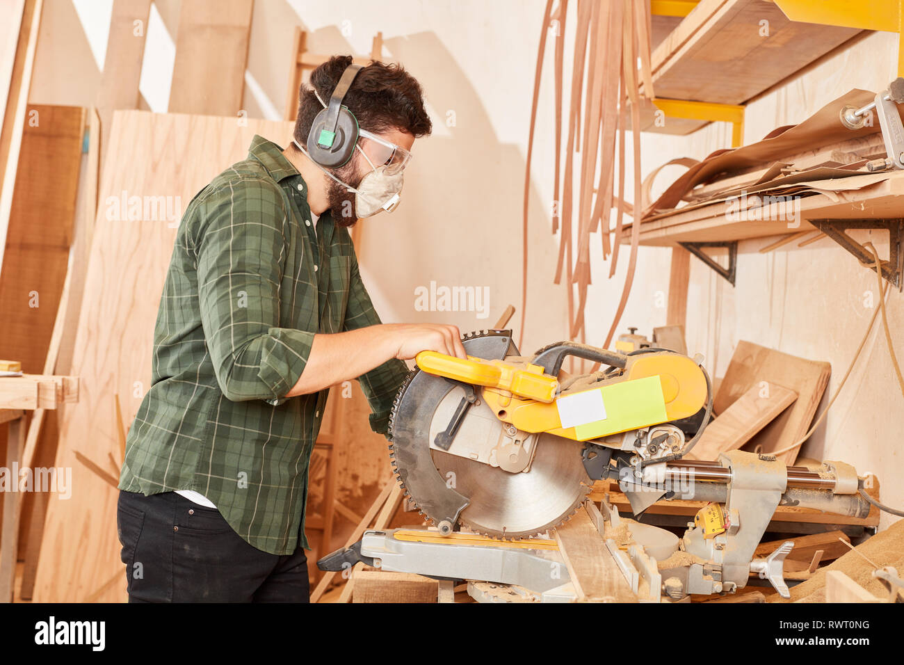 Heimwerker mit Gehörschutz und Atemschutzmaske auf die Säge in der  Tischlerei Stockfotografie - Alamy
