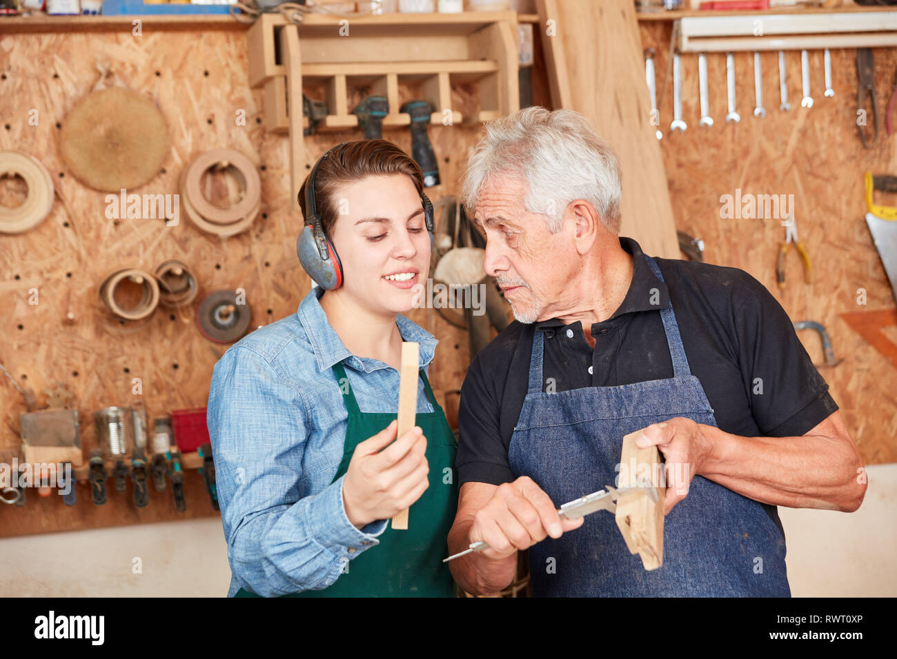 Handwerker Lehrling und Tischler Meister Holz mit Messschieber messen. Stockfoto