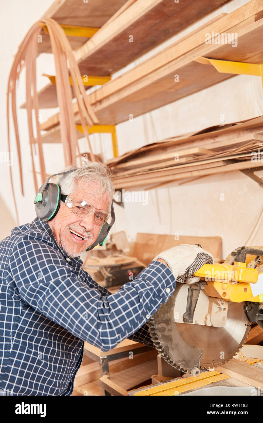 Schreiner Meister mit Gehörschutz Sägt Holz an der Säge in der Werkstatt chop Stockfoto