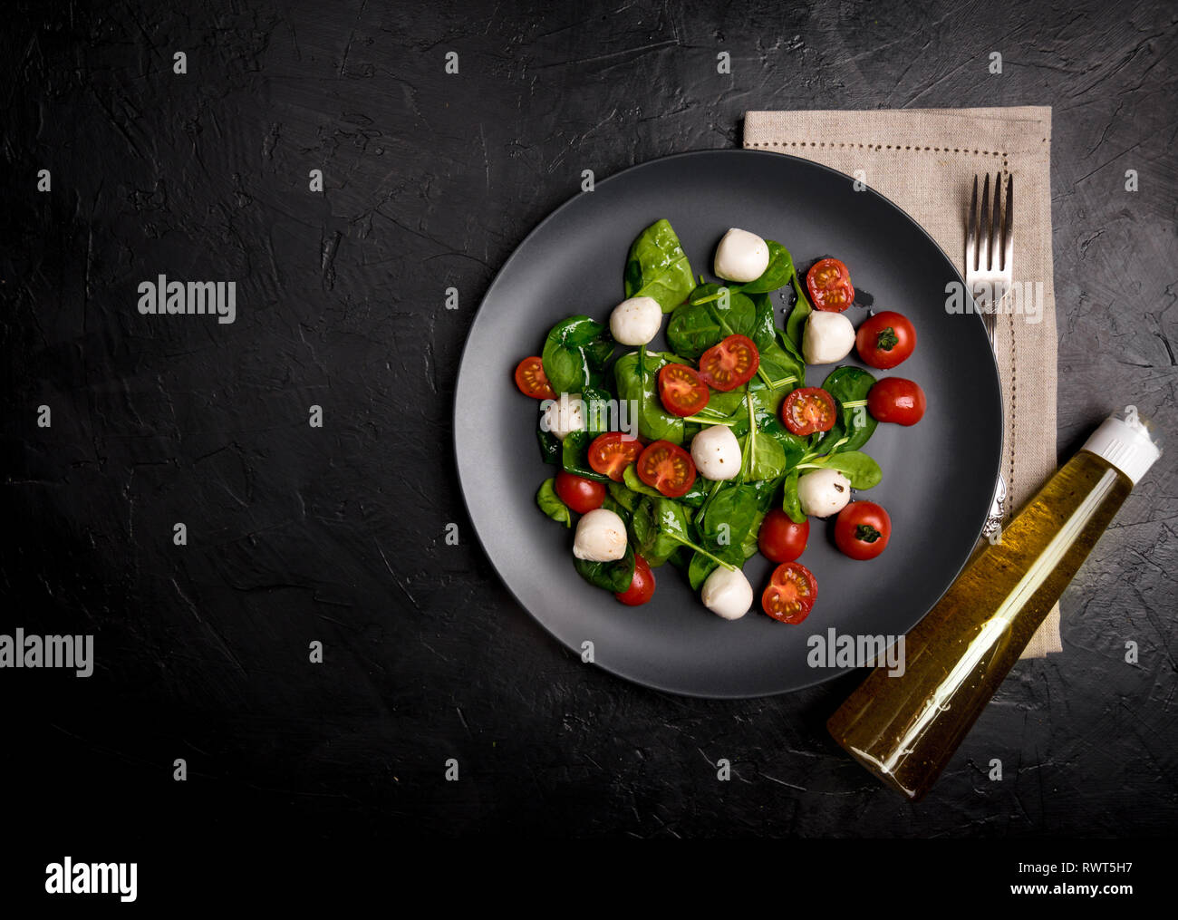 Salat mit Mozzarella und Baby Spinat auf schwarze Keramikplatte ...