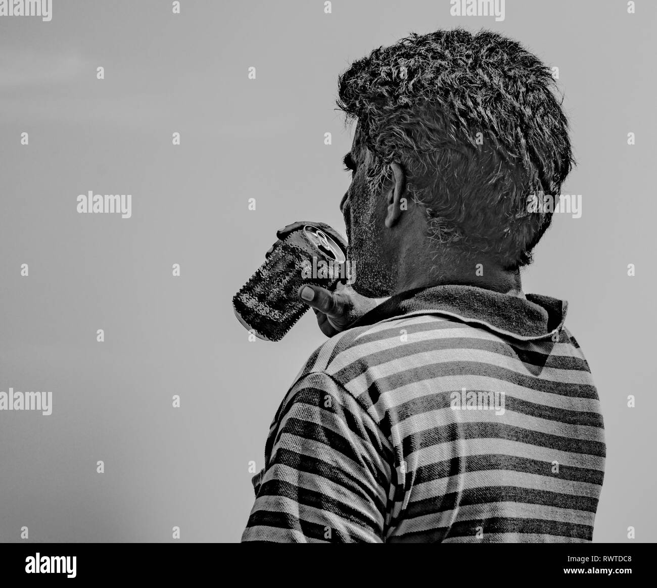 Schwarz-weiß Foto von mittleren Alter Mann, der gestreifte T-Shirt und Durst durch das Trinken von Bier/kaltes Getränk aus Aluminium kann an heißen, sonnigen Tag Stockfoto