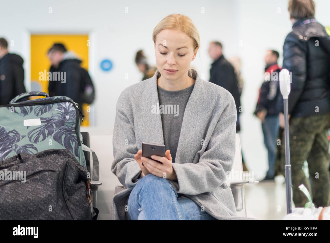 Weibliche Reisende können Sie über Ihr Handy während der Wartezeit in ein Flugzeug steigen bei der Abreise Gates am Flughafen. Stockfoto