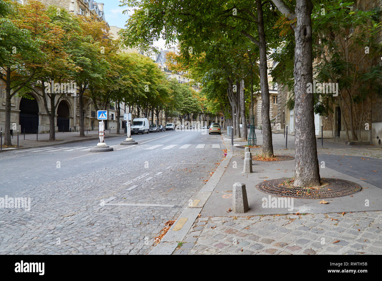 PARIS, Frankreich, 23. JULI 2017: Leere Pariser Straße und Bürgersteig mit grünen Bäumen in einem Sommertag in Paris, Frankreich Stockfoto
