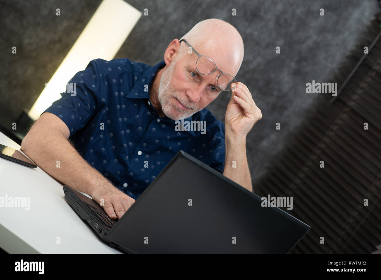 Ein älterer Geschäftsmann mit Laptop, er Schwierigkeiten und Sehstörungen Stockfoto