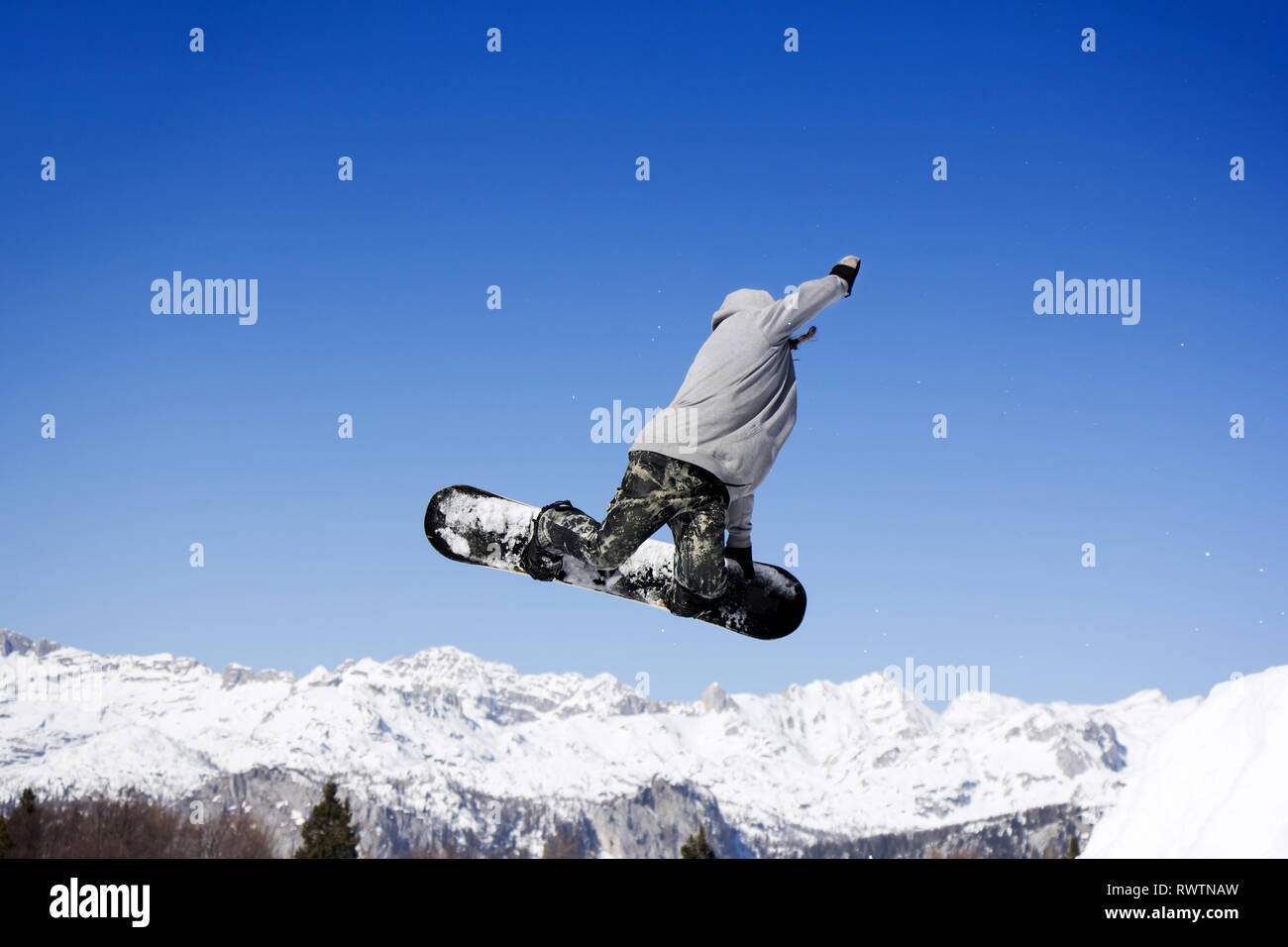 Extreme Snowboarder am Sprung über Berge springen an einem sonnigen Tag Stockfoto
