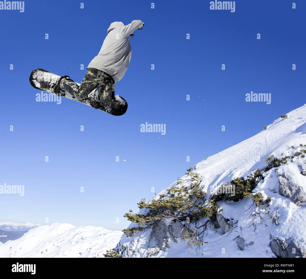 Extreme Snowboarder am Sprung über Berge springen an einem sonnigen Tag Stockfoto