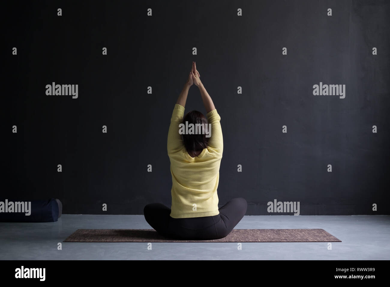 Rückansicht der reifen Frau in Pullover in Yoga sitting Pose Stockfoto