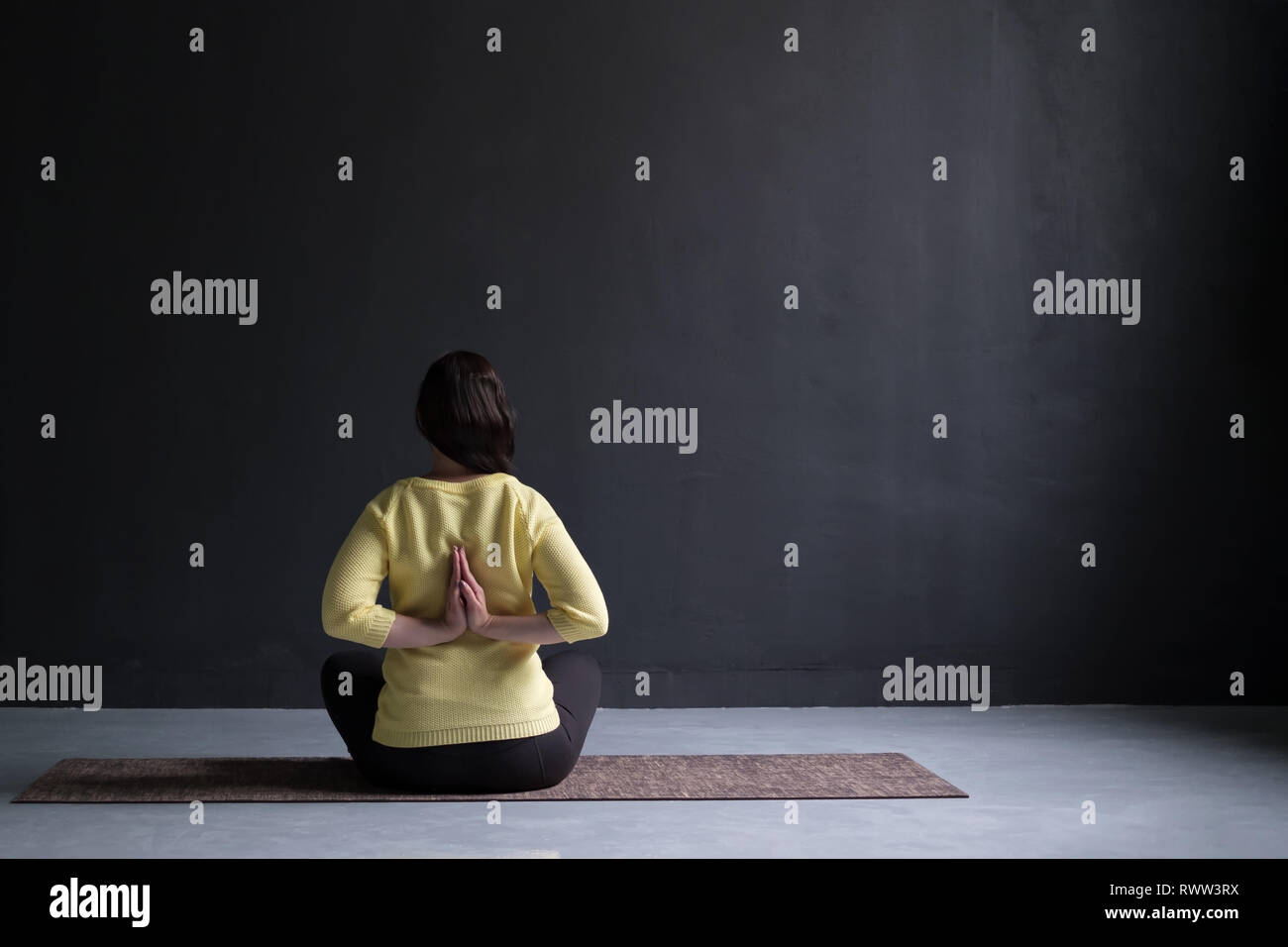 Rückansicht der reifen Frau in Pullover in Yoga sitting Pose Stockfoto