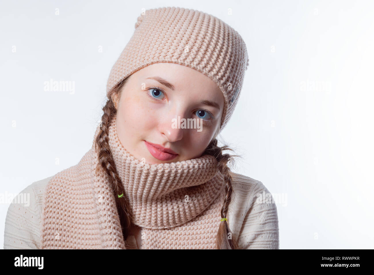 Schöne Mädchen mit blauen Augen und Weidenkörbe flechten in einem gestrickte Mütze und Schal. Hellen Hintergrund mit leeren Raum Stockfoto