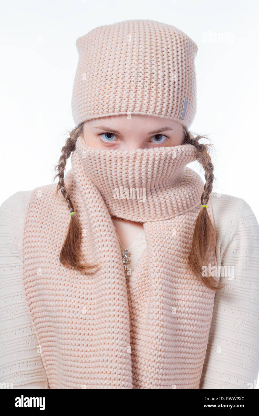 Ein Mädchen mit blauen Augen und Pigtails verbirgt ihr Gesicht hinter einem strickschal. Der Blick in die Kamera Stockfoto