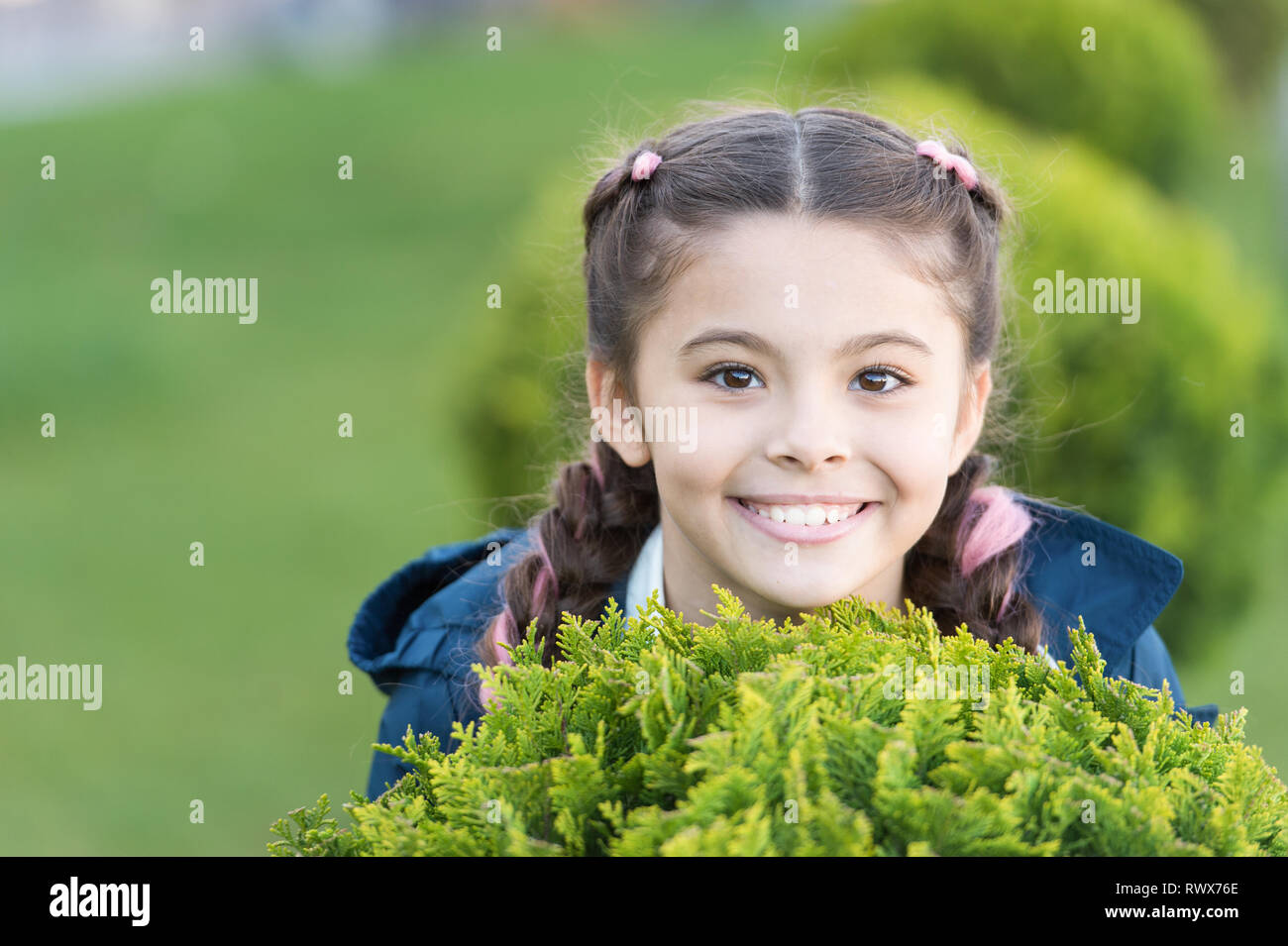Mädchen süß lächelnd Kid grünes Gras Hintergrund. Gesunde emotionale glückliches Kind Entspannung im Freien. Was macht Kinder glücklich. Mädchen Zöpfe Frisur entspannen. Gerne ausblenden Spiel im Freien. Ausblenden und Spaß suchen. Stockfoto