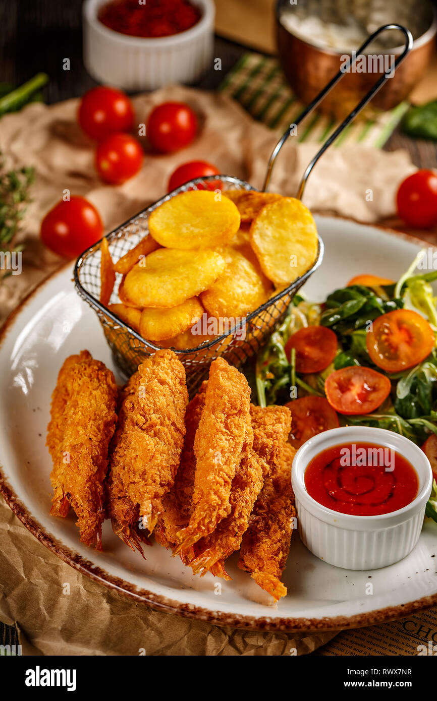 Gebratene Garnelen tempura mit Sweet Chili Sauce, frischer Salat und Bratkartoffeln Stockfoto