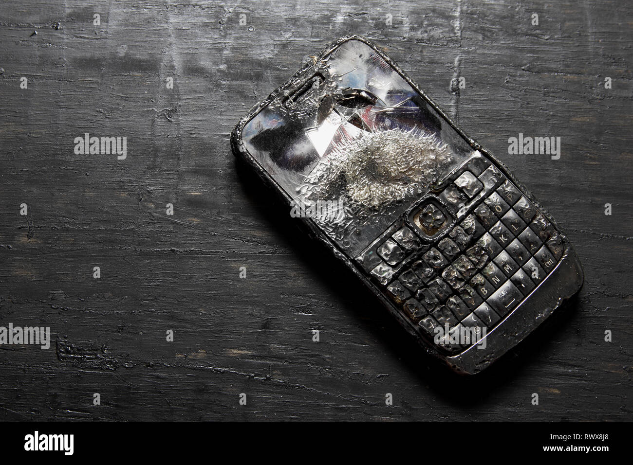 Verbrannt Mobiltelefon auf hölzernen Hintergrund Stockfoto