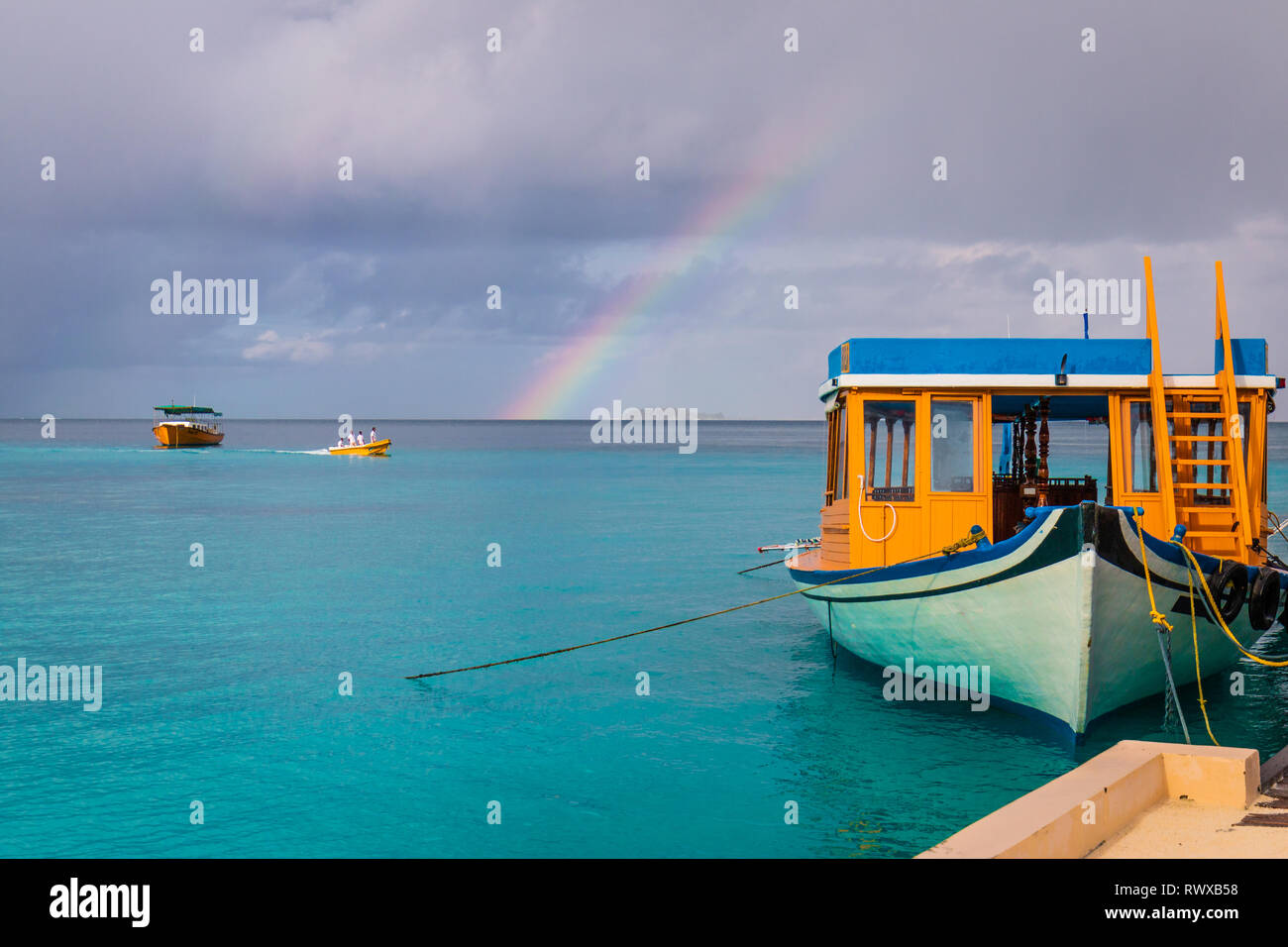 Regenbogen im Paradies - wunderschöne Regenbogen auf den Malediven mit Booten in den Vordergrund und Hintergrund Stockfoto