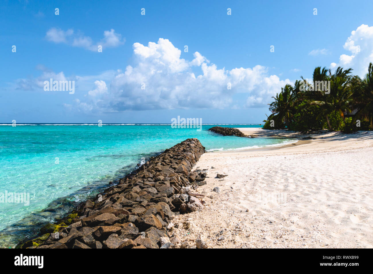 Strand auf den Malediven mit Steinen im Vordergrund - ein Paradies Stockfoto