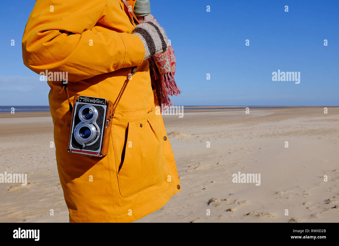 Person, die Retro Vintage Kamera über Schultergurt, holkham Beach, North Norfolk, England Stockfoto