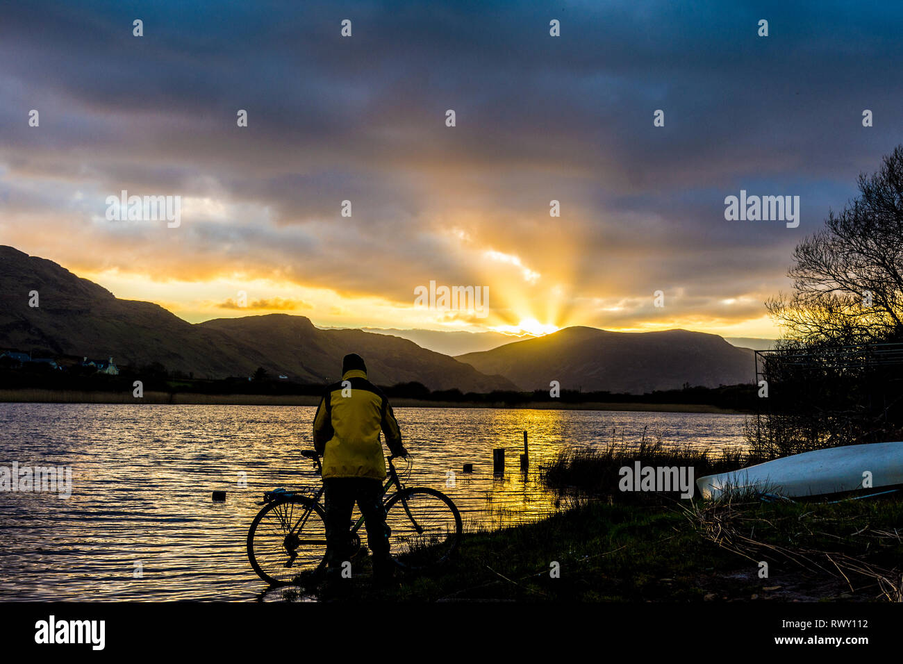 Ardara, County Donegal, Irland. 7. März 2019. Ein Radfahrer hält den Sonnenuntergang über dem See Shanaghan zu beobachten. Credit: Richard Wayman/Alamy leben Nachrichten Stockfoto