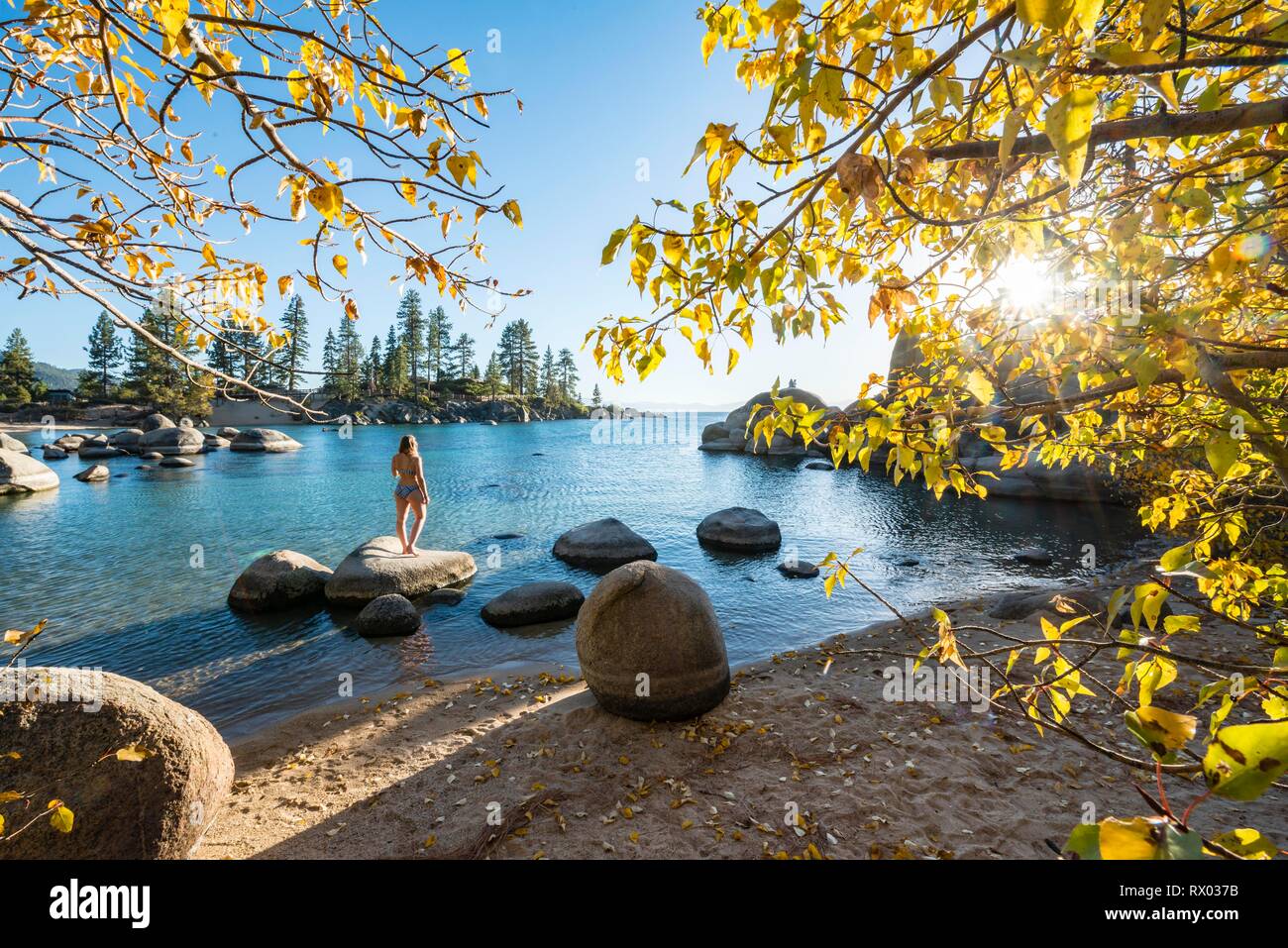 Junge Frau im Bikini stehen auf einem runden Stein im Wasser, Bay am Lake Tahoe, Sand Harbor State Park, Ufer, Kalifornien Stockfoto