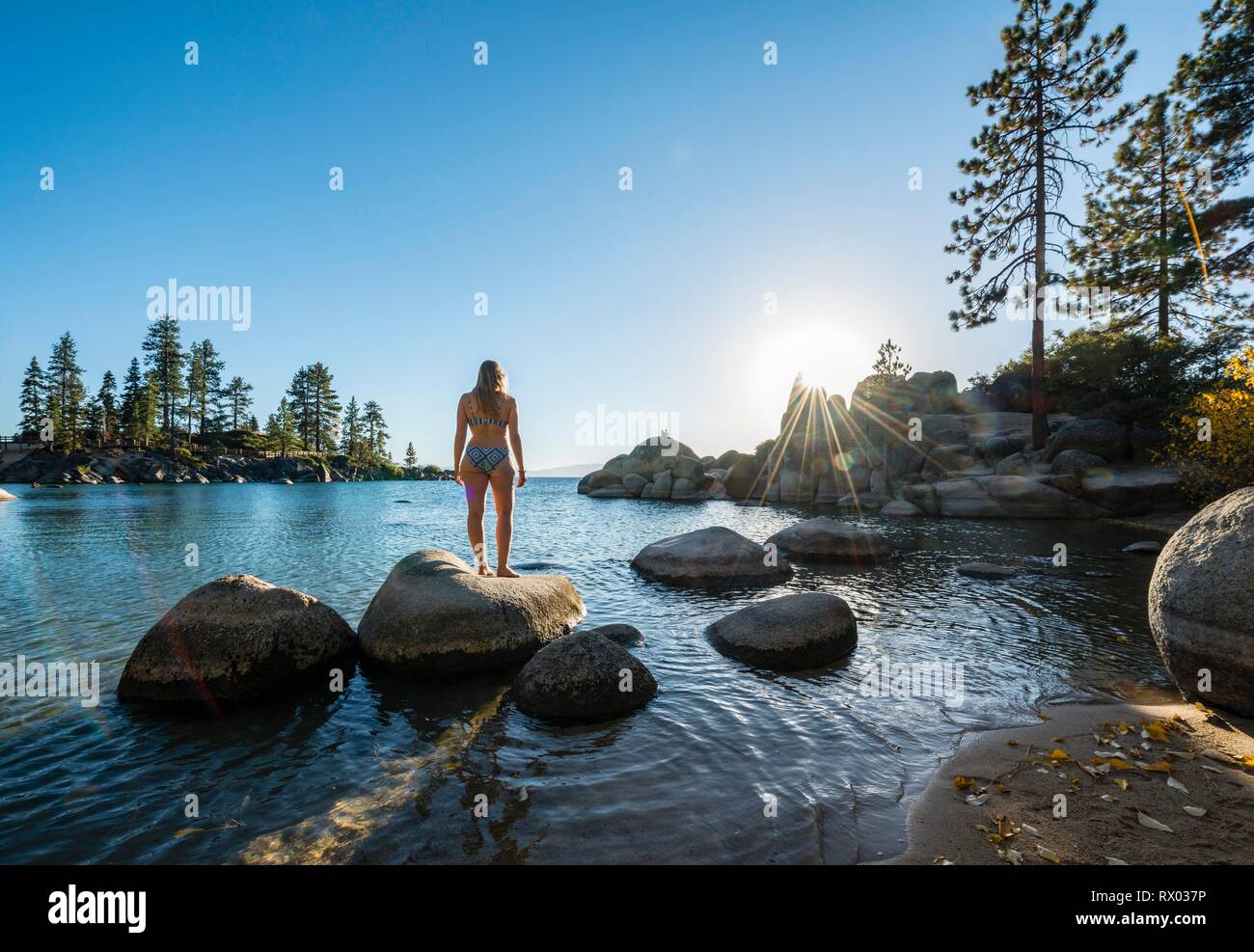 Junge Frau im Bikini stehen auf einem runden Stein im Wasser, Bay am Lake Tahoe, Sand Harbor State Park, Ufer, Kalifornien Stockfoto