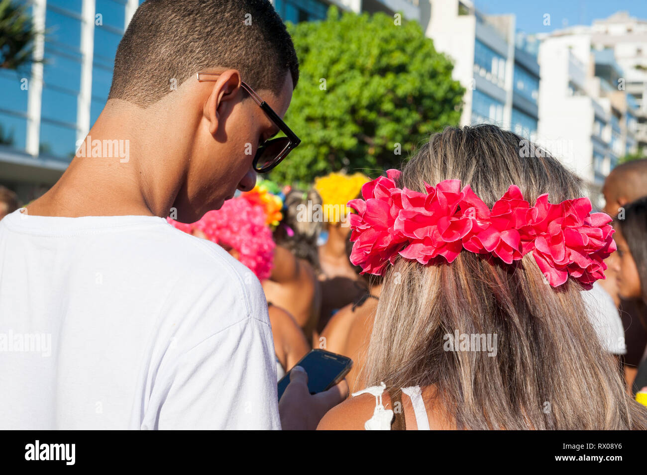 RIO DE JANEIRO - 11. FEBRUAR 2017: ein paar junge Brasilianer ihre Smartphones an einem Nachmittag banda Karneval Straßenfest in Ipanema prüfen. Stockfoto
