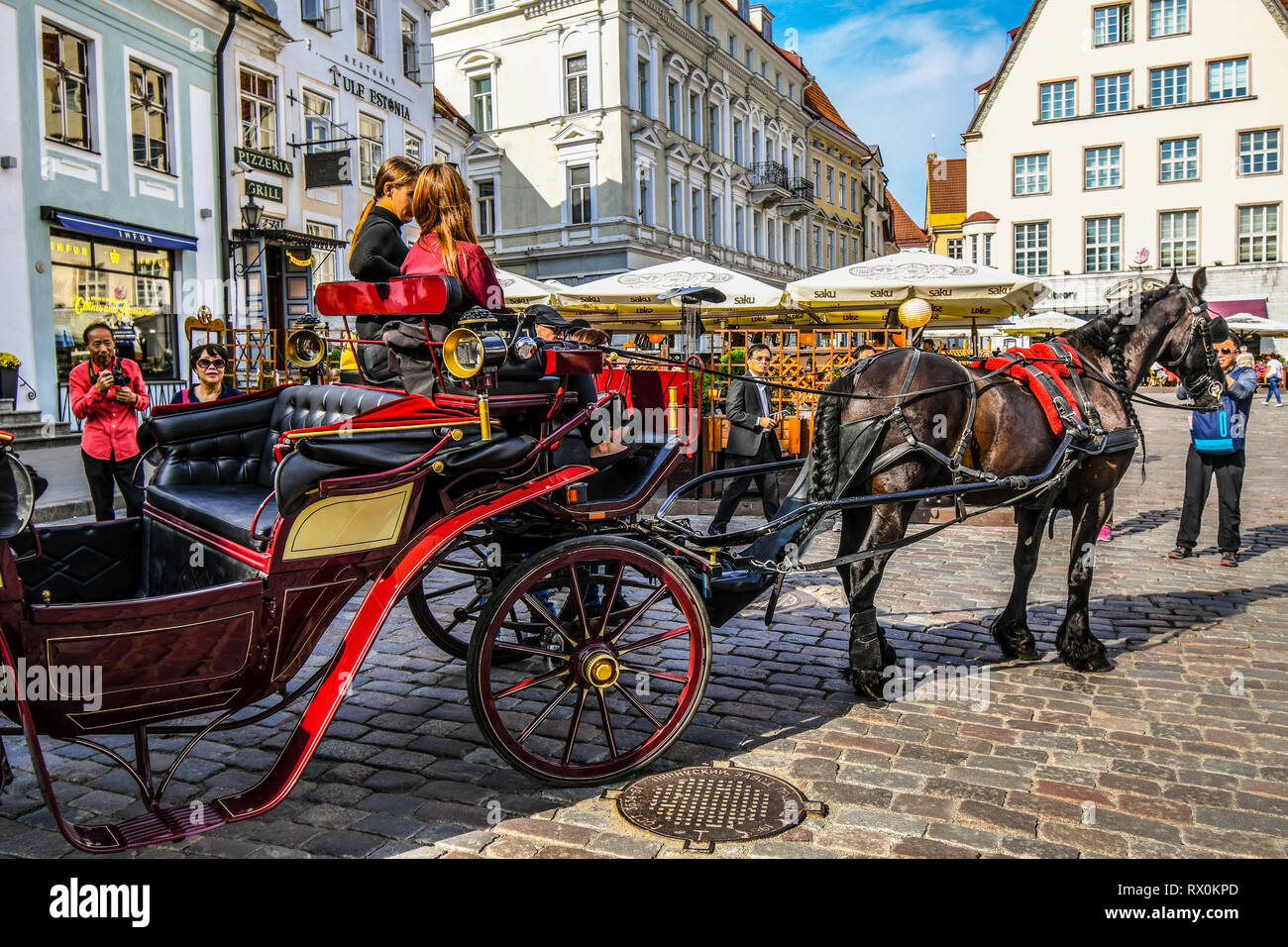 Eine Pferdekutsche und Reiter für die Fahrt in die Stadt an einem langen Sommertag mit Touristen, die mittelalterlichen Gassen, Bars und Cafes Stockfoto