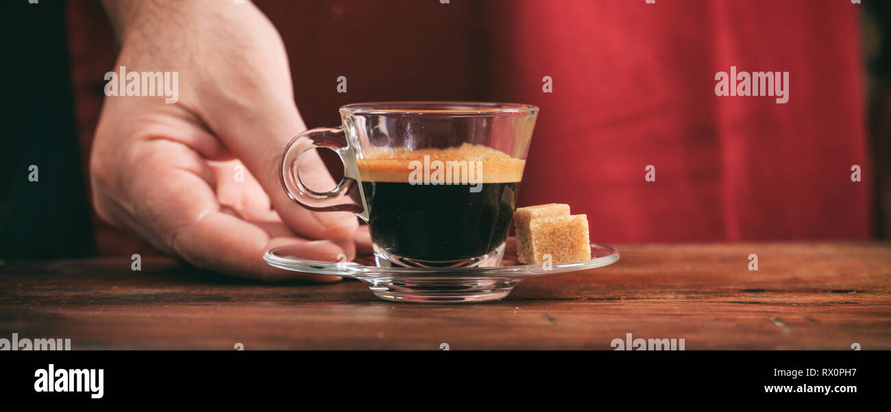 Espresso. Kellner ein Glas Schale auf hölzernen Tisch serviert werden, Banner, Detailansicht Stockfoto