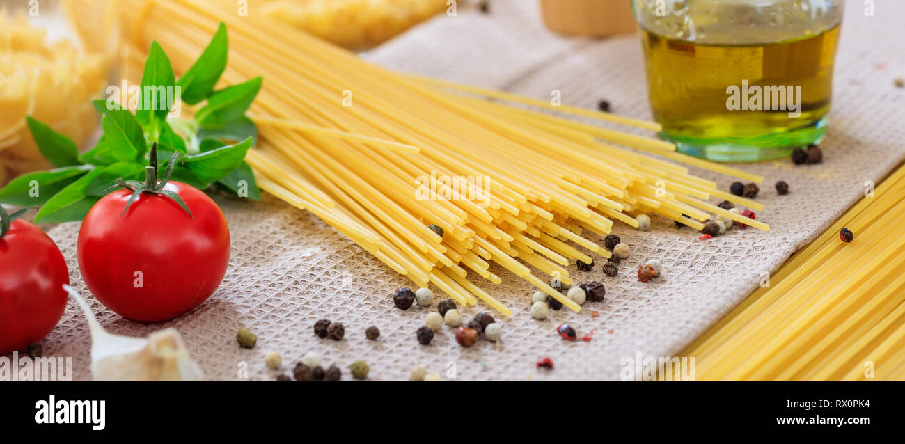 Italienisches Essen Vorbereitung. Spaghetti Pasta, Tomaten, Knoblauch und Pfeffer Samen, Banner Stockfoto