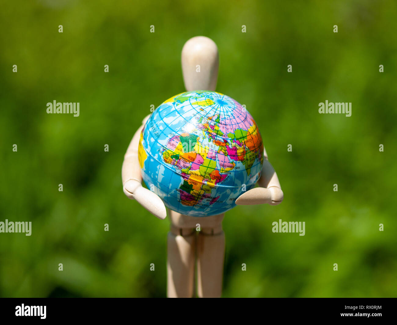 Eine hölzerne Puppe mit einer Welt Kugel in seine Arme. Ökologie Konzept, Globalisierung Stockfoto