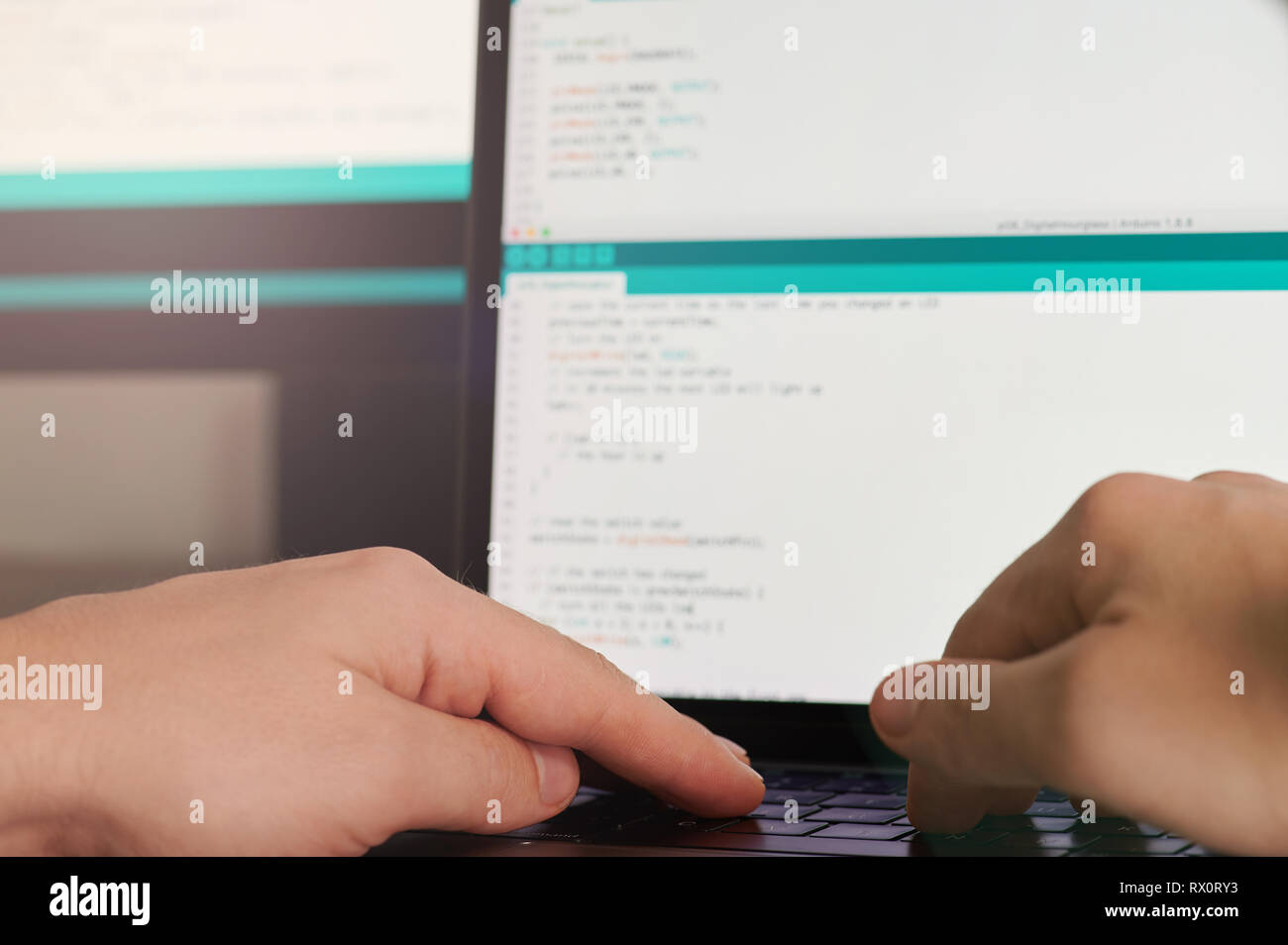 Software Entwicklung Thema. Hände auf Laptop Tastatur in unscharfer Monitor Hintergrund Stockfoto
