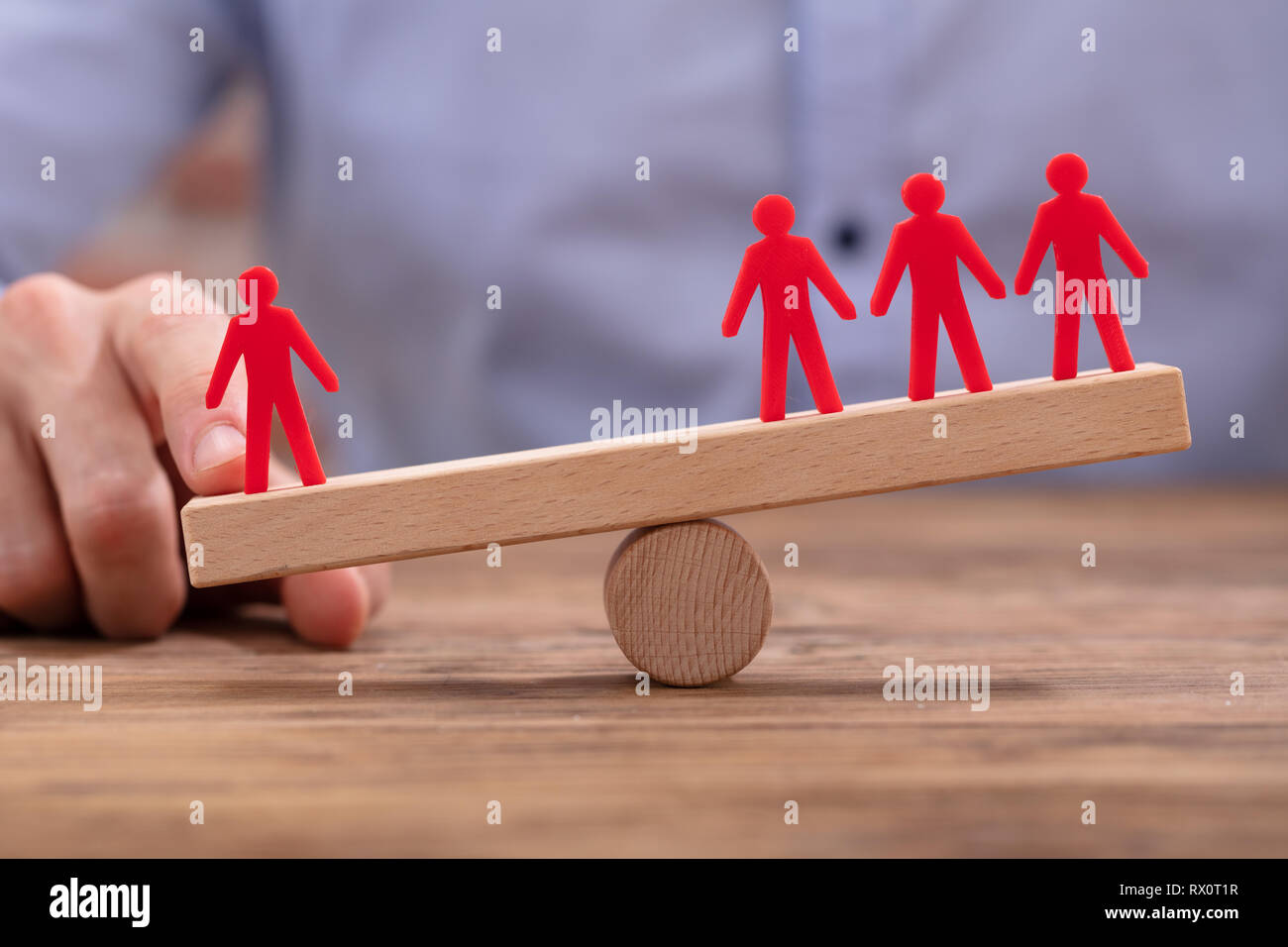 Der Geschäftsmann, Hand, Ungleichgewicht zwischen den roten Zahlen auf Wippe über Holz- Schreibtisch Stockfoto