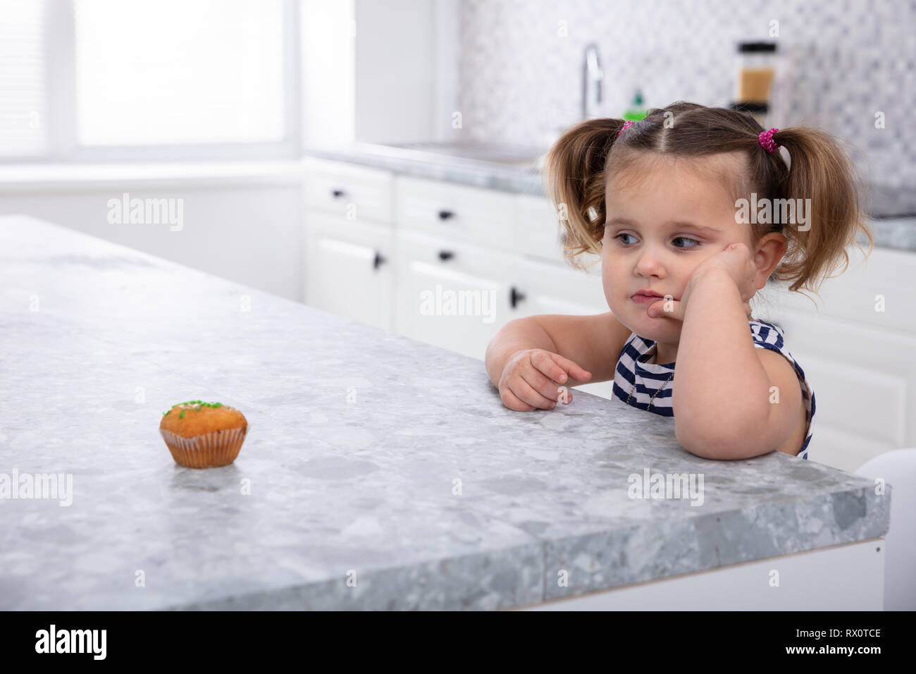 In der Nähe von Mädchen an Cupcake Suche auf der Küchenarbeitsplatte Stockfoto