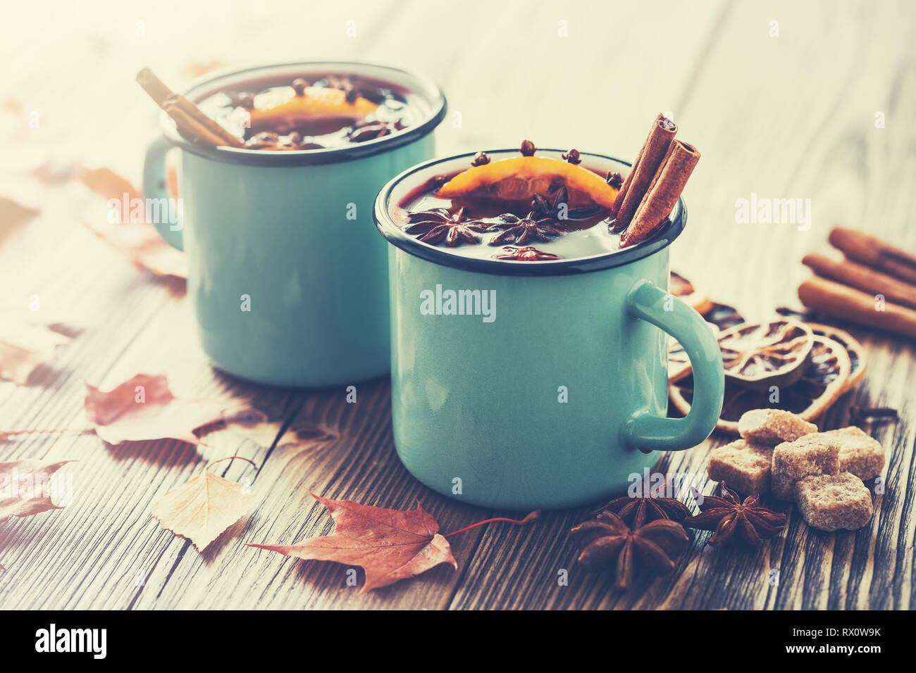 Glühwein in blau emailliert rustikalen Becher mit Gewürze und Zitrusfrüchte auf Holztisch mit Blätter im Herbst. Retro Farben Foto. Stockfoto