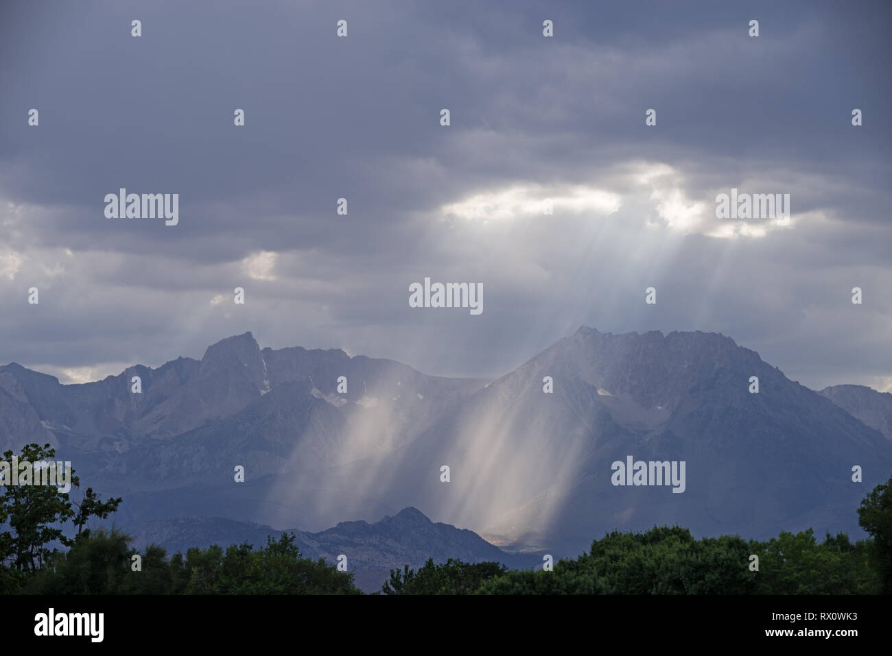 Die Sonnenstrahlen scheinen durch eine Lücke in den Wolken und Regen über die Sierra Berge von Bischof Kalifornien Stockfoto