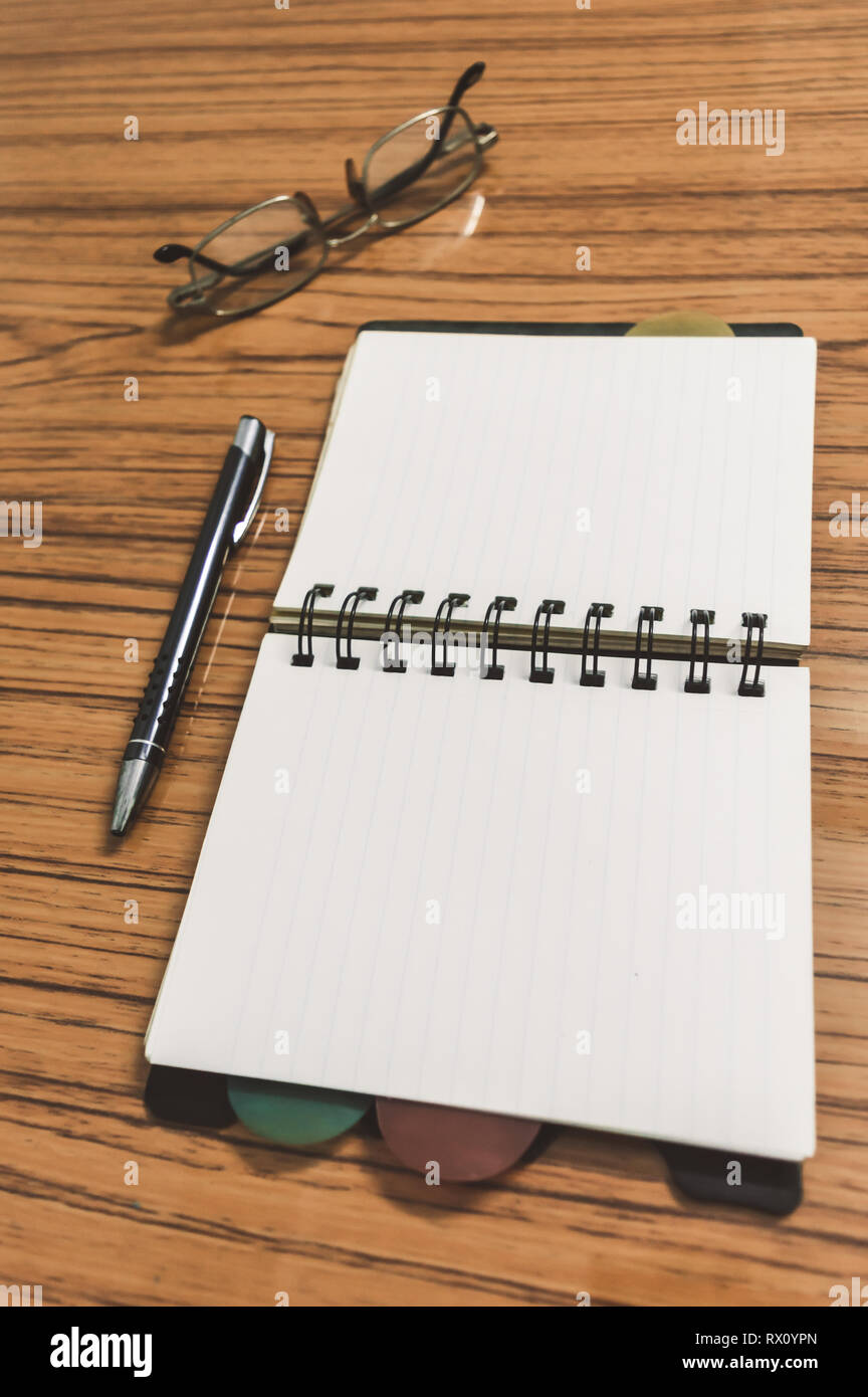 Schreibtisch mit offenen Notebook mit leeren Seiten, Brillen und einen Stift. Business still life Konzept mit Office Material auf dem Tisch. Bildung, Arbeit und planni Stockfoto