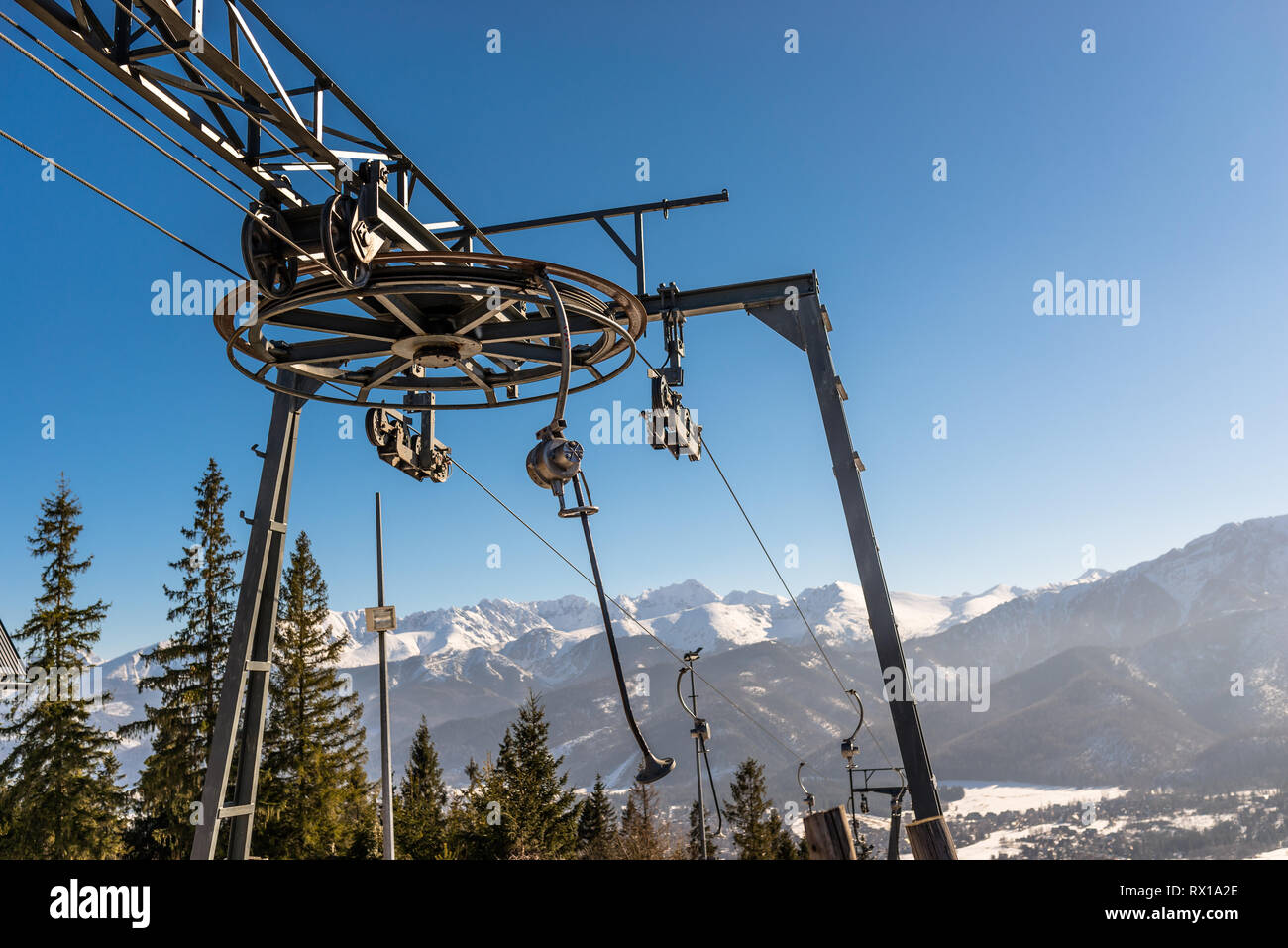 Der Mechanismus der Skilift, sichtbar groß, Antriebsrad Ziehen am Seil und hängenden Stühle im Hintergrund Berge und Bäume. Stockfoto