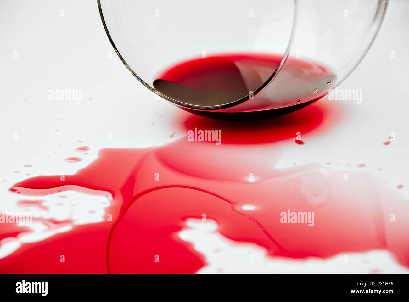 Rotwein verschüttet aus einem Weinglas auf eine weiße Fläche Stockfoto