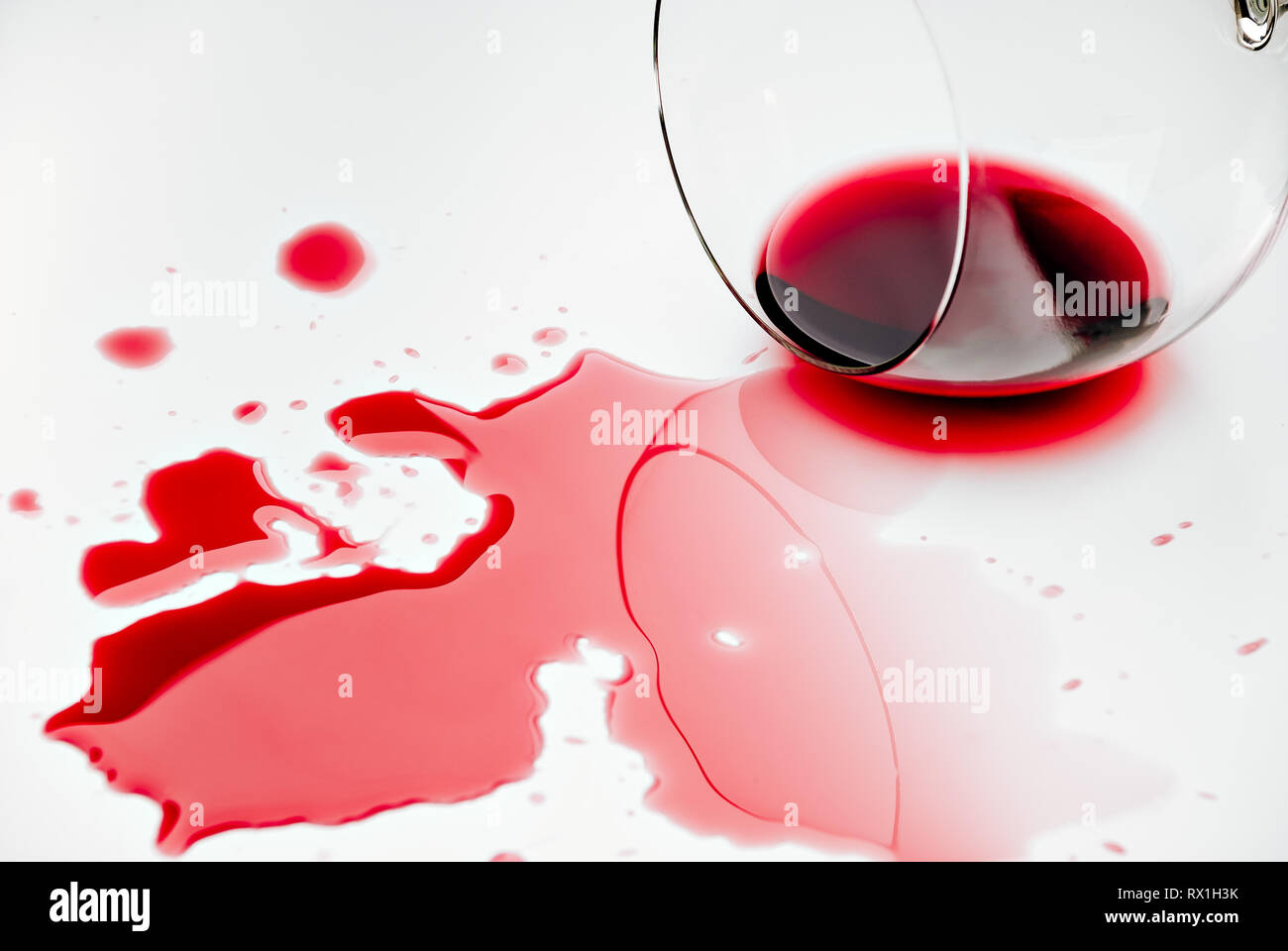 Rotwein verschüttet aus einem Weinglas auf eine weiße Fläche Stockfoto