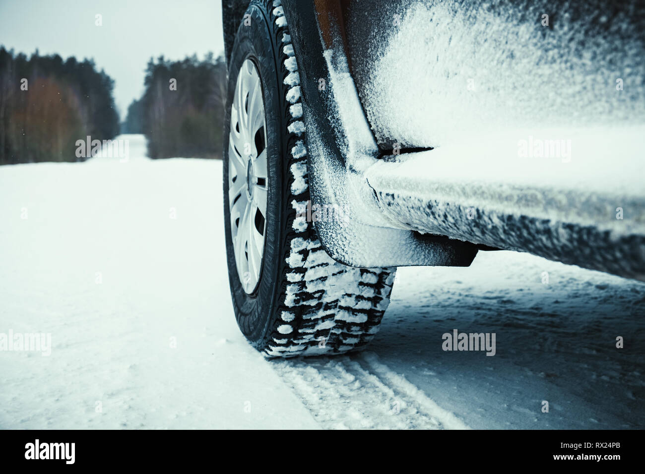 Pkw-Reifen Winter mit Schnee auf der Straße durch Wald bedeckt. Stockfoto