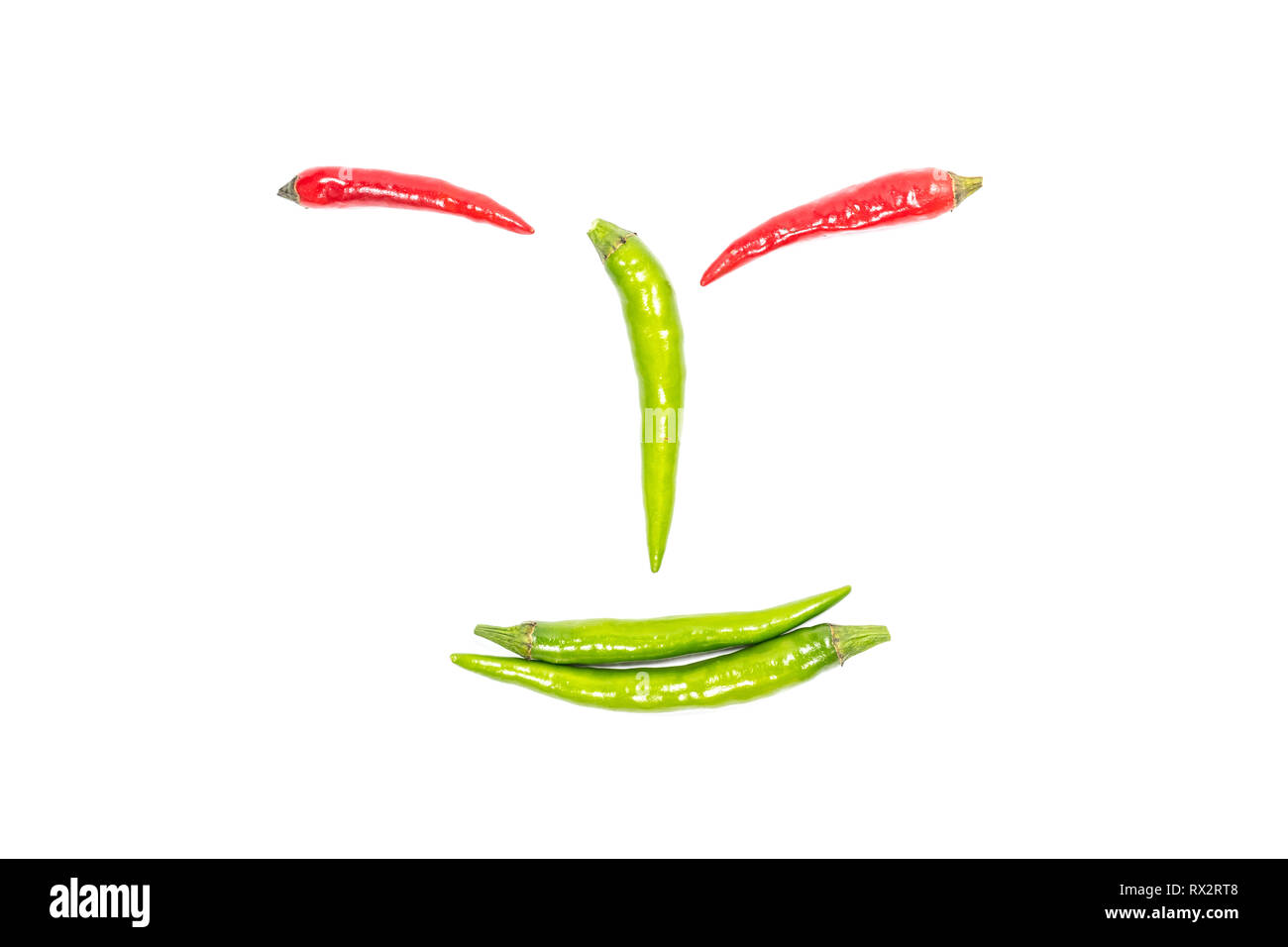 Grüne Chilis in ein Smiley auf weißem Hintergrund angeordnet. Stockfoto