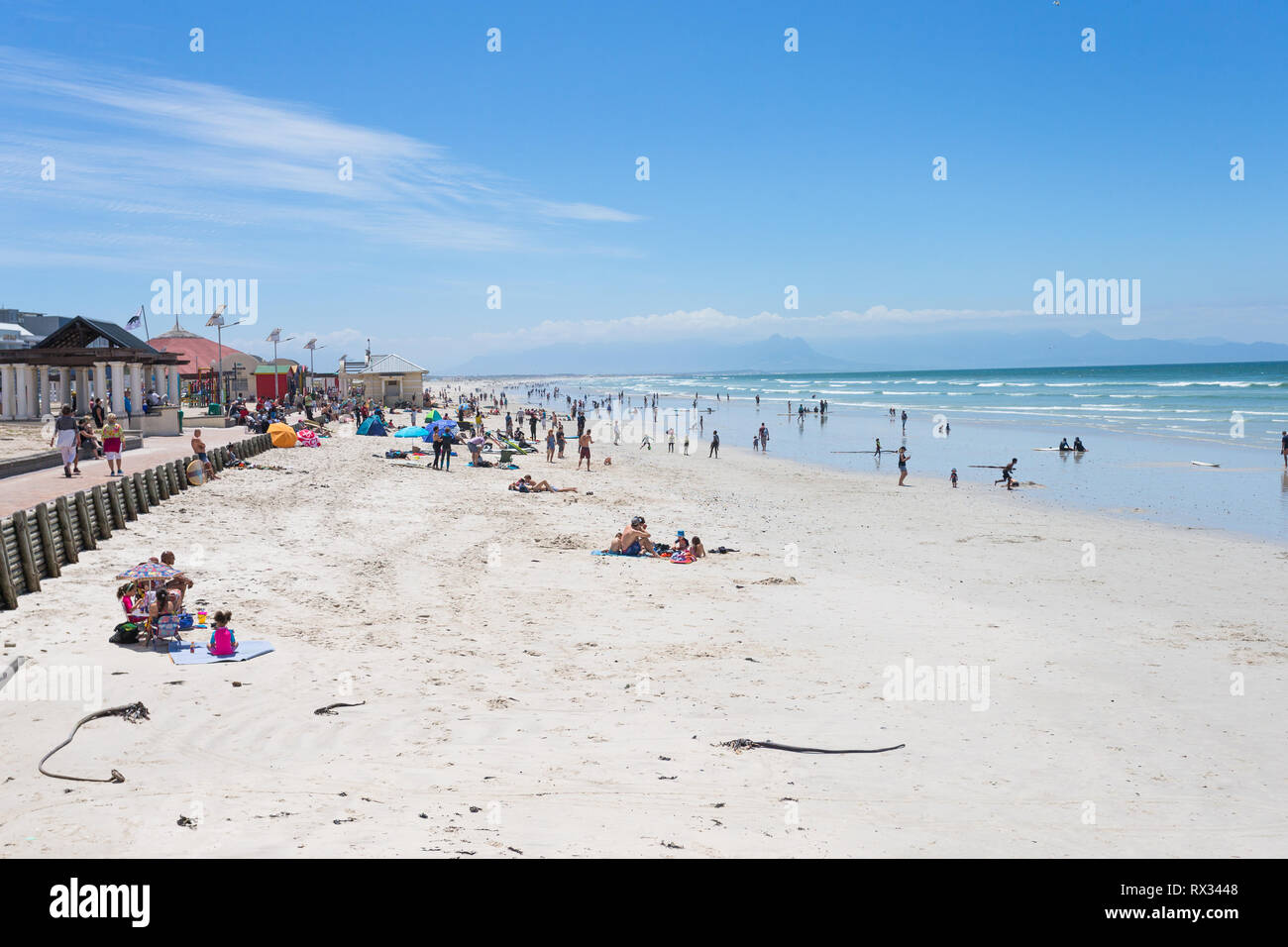 Massen von Menschen oder beachgoers genießen einige Spaß am Strand an einem sonnigen Tag Sommer in Muizenberg, False Bay, Cape Peninsula, Cape Town, Südafrika Stockfoto