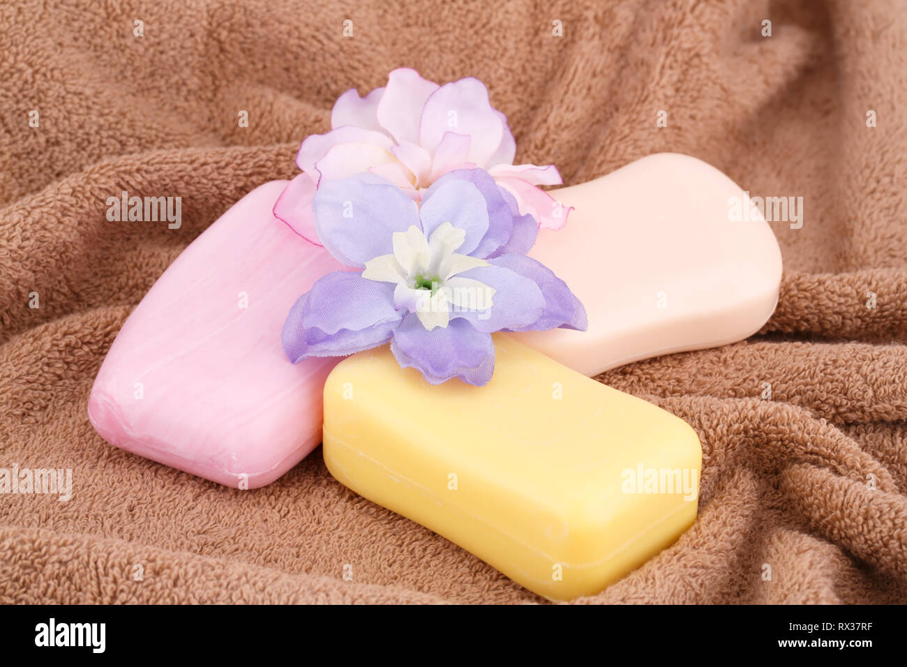 Bunte Seifen und Blumen auf braun Handtuch. Stockfoto