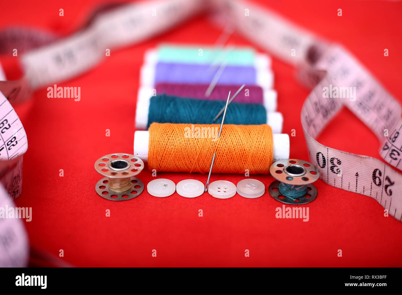 Bild von Threads, Nadeln, Spulen, Maßband und Knopf. Auf dem roten Hintergrund. Stockfoto
