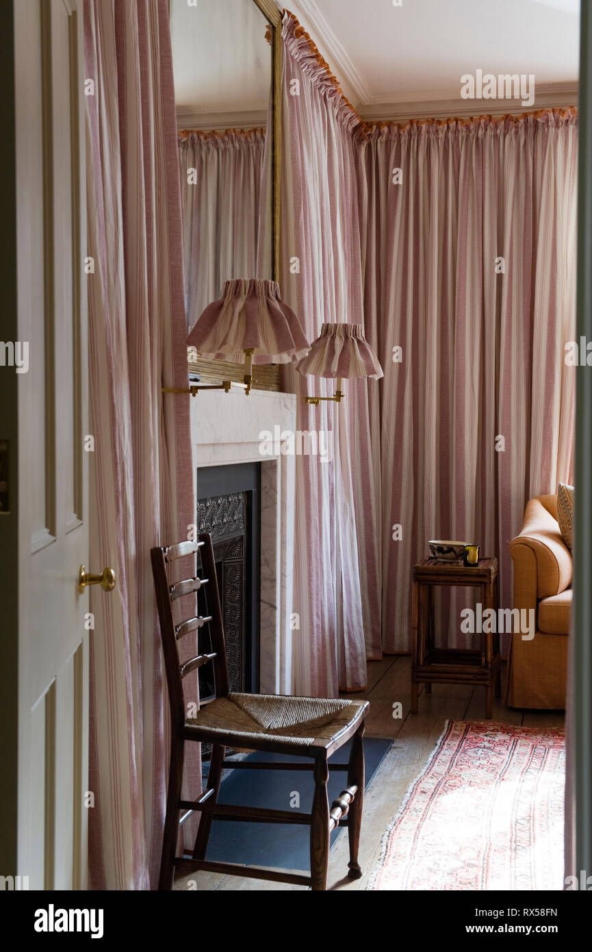 Kamin im Schlafzimmer mit pinkfarbenen Vorhängen bedeckt Stockfoto