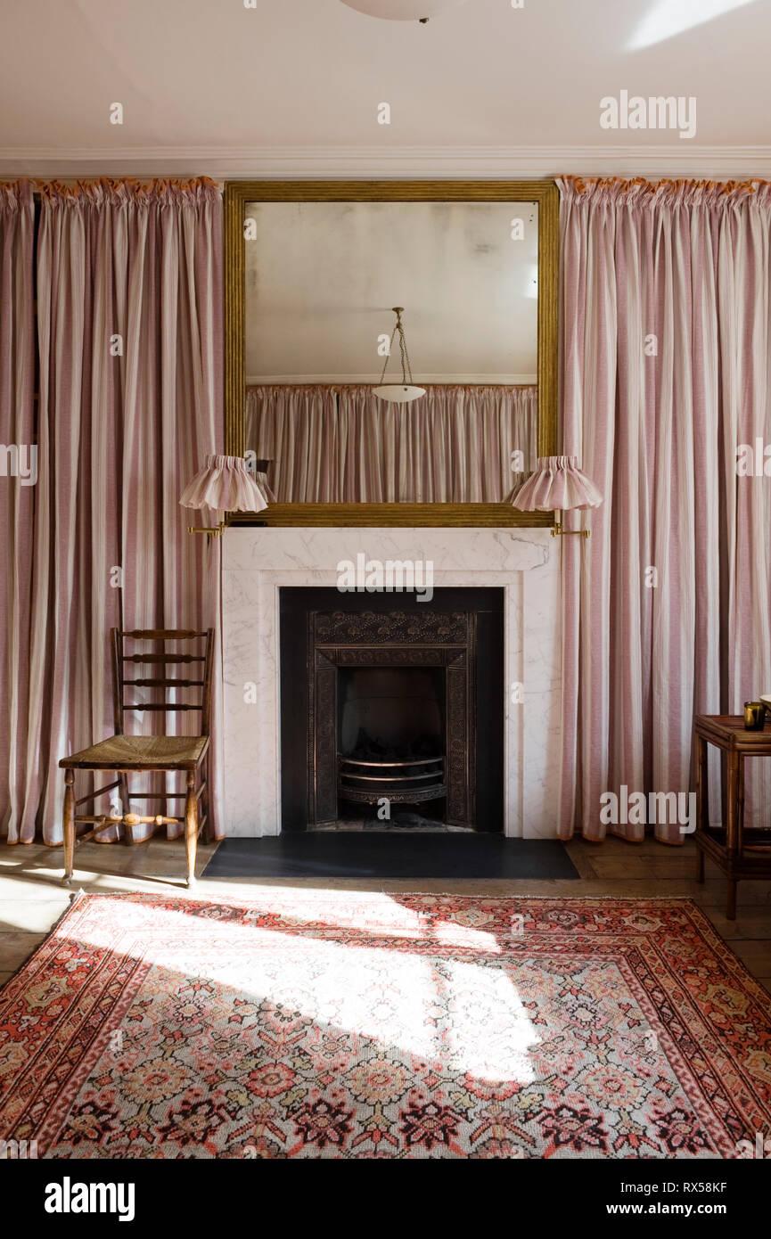 Kamin im Schlafzimmer mit pinkfarbenen Vorhängen bedeckt Stockfoto