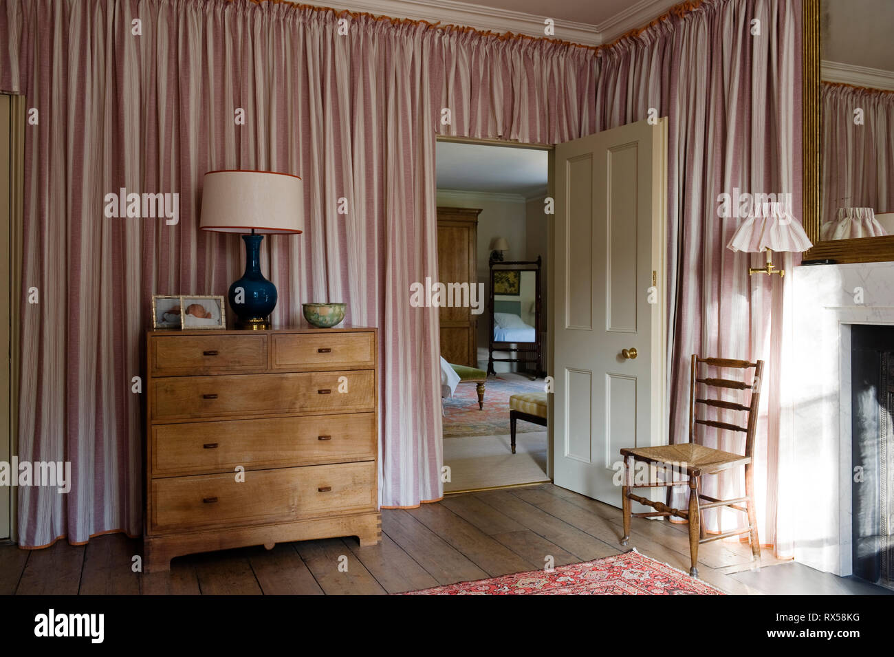 Tallboy im Schlafzimmer mit pinkfarbenen Vorhängen bedeckt Stockfoto