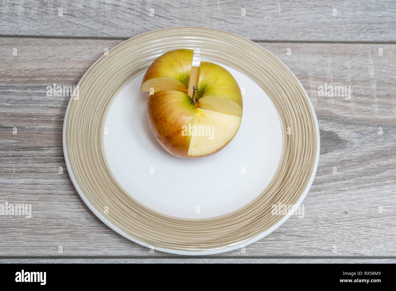 Ein Schnitt Apple auf einem weißen Teller auf dem hölzernen Tisch Stockfoto
